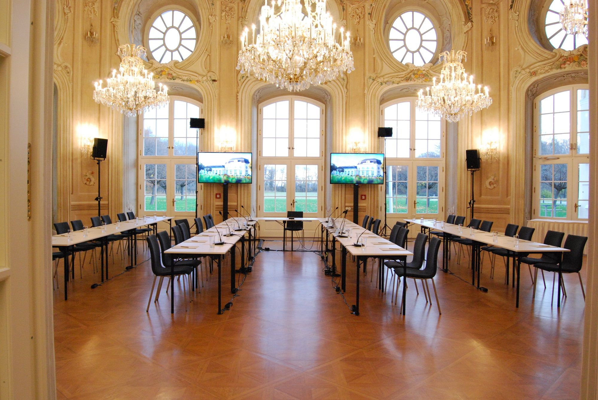 Elegantní konferenční místnost s lustry a velkými okny.