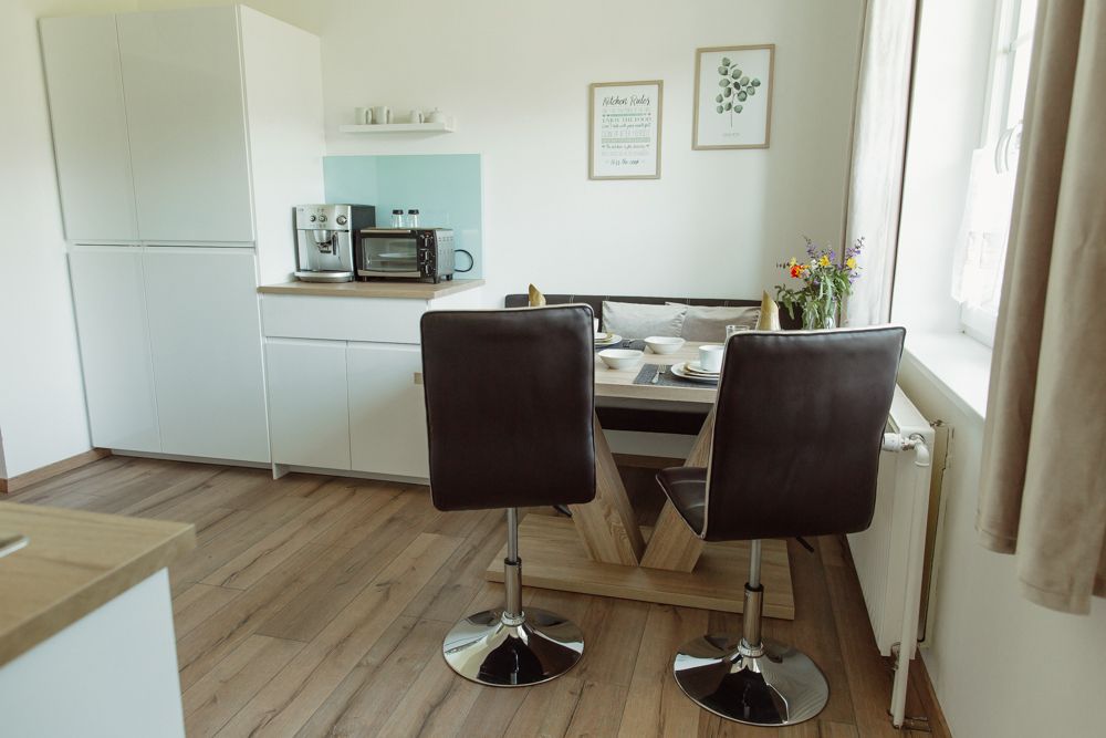 Moderní kuchyně s jídelním stolem, židlemi a spotřebiči.