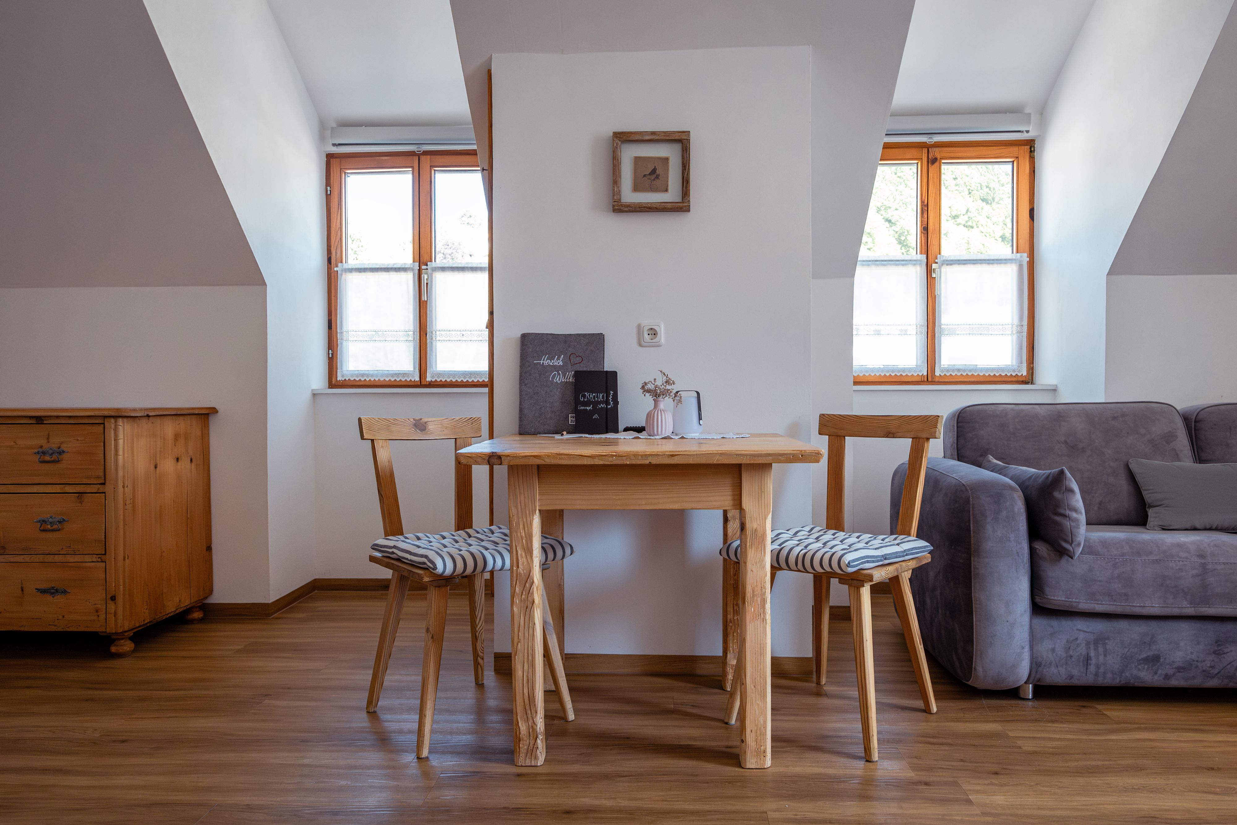 Útulný obývací prostor s dřevěným stolem, dvěma židlemi a pohovkou.