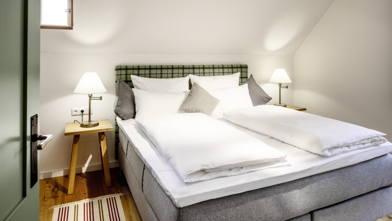 Útulný hotelový pokoj s manželskou postelí, nočními stolky a lampičkami.