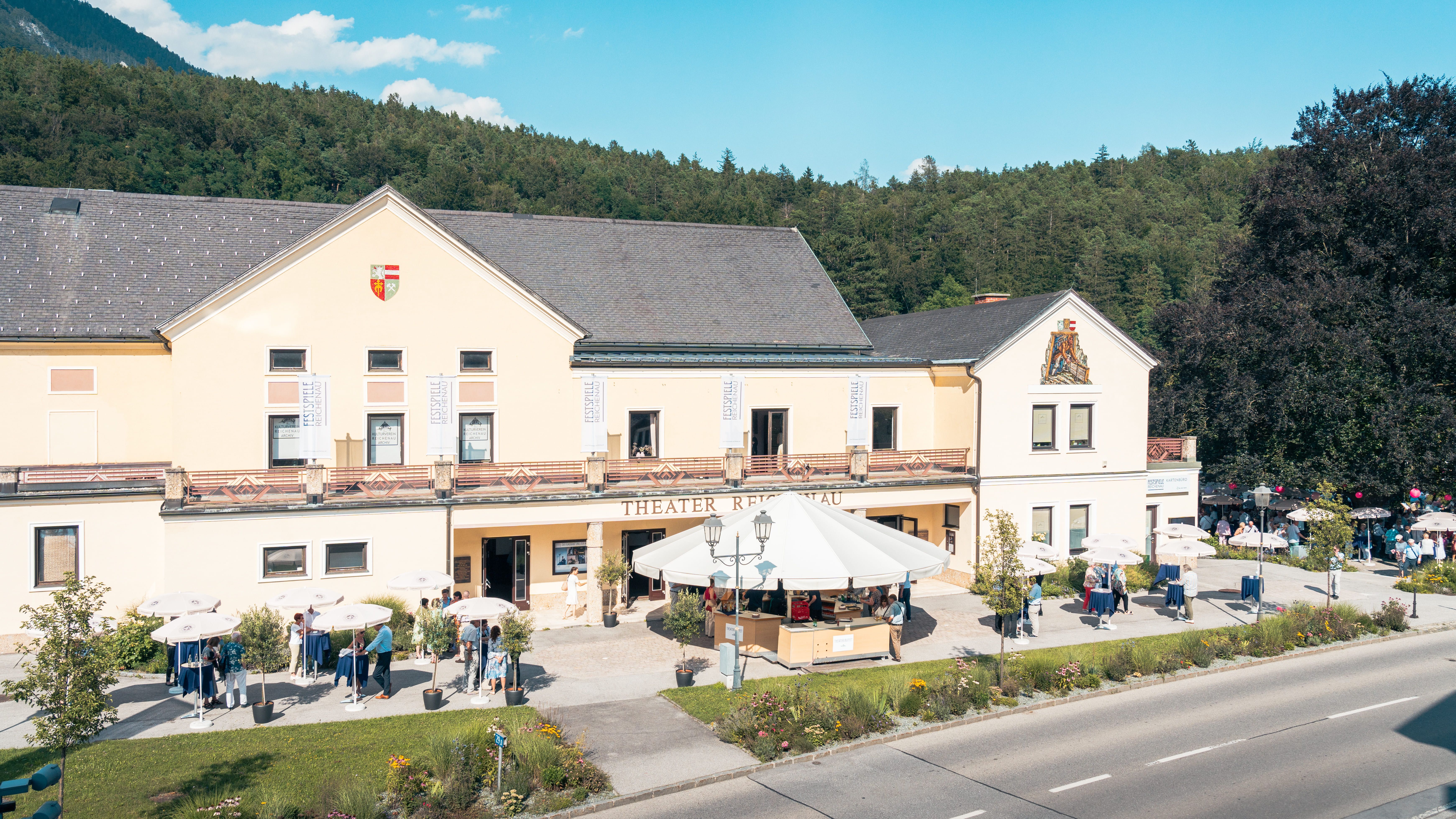 Divadlo Reichenau s lidmi a slunečníky před ním.