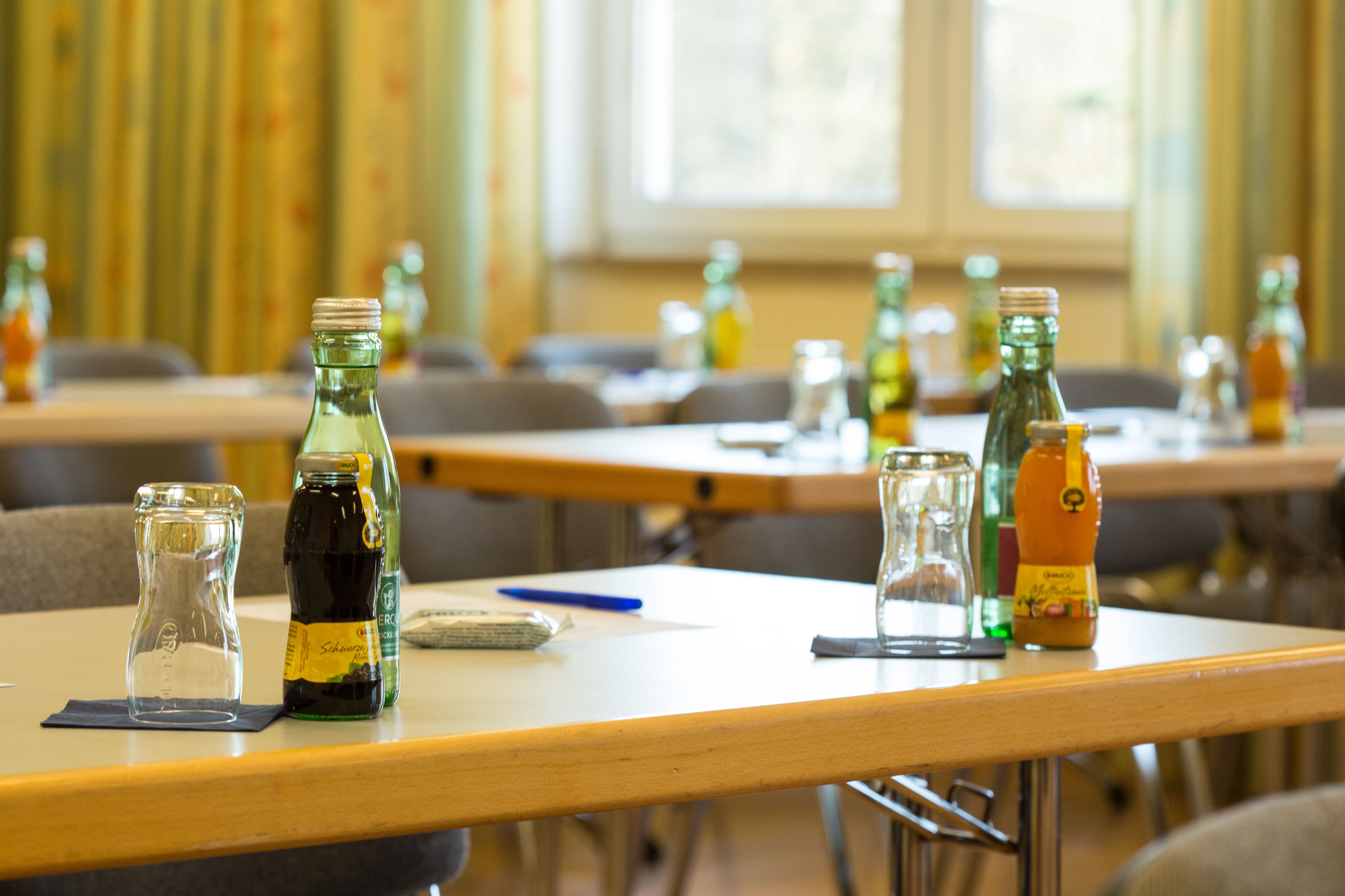 Seminární místnost se stoly, na kterých jsou umístěny nápoje a sklenice.