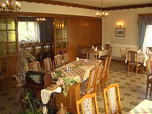 Pohled do interiéru tradičního hostince s dřevěným nábytkem a zdobenými stoly.