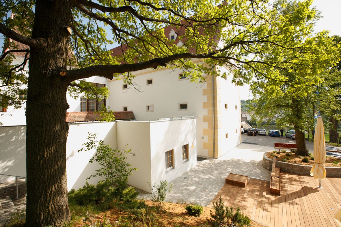 Vnější pohled na Schüttkasten Geras se stromy a terasou.