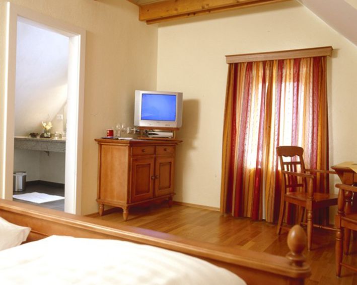 Útulný pokoj s dřevěným nábytkem, TV a barevnými závěsy.