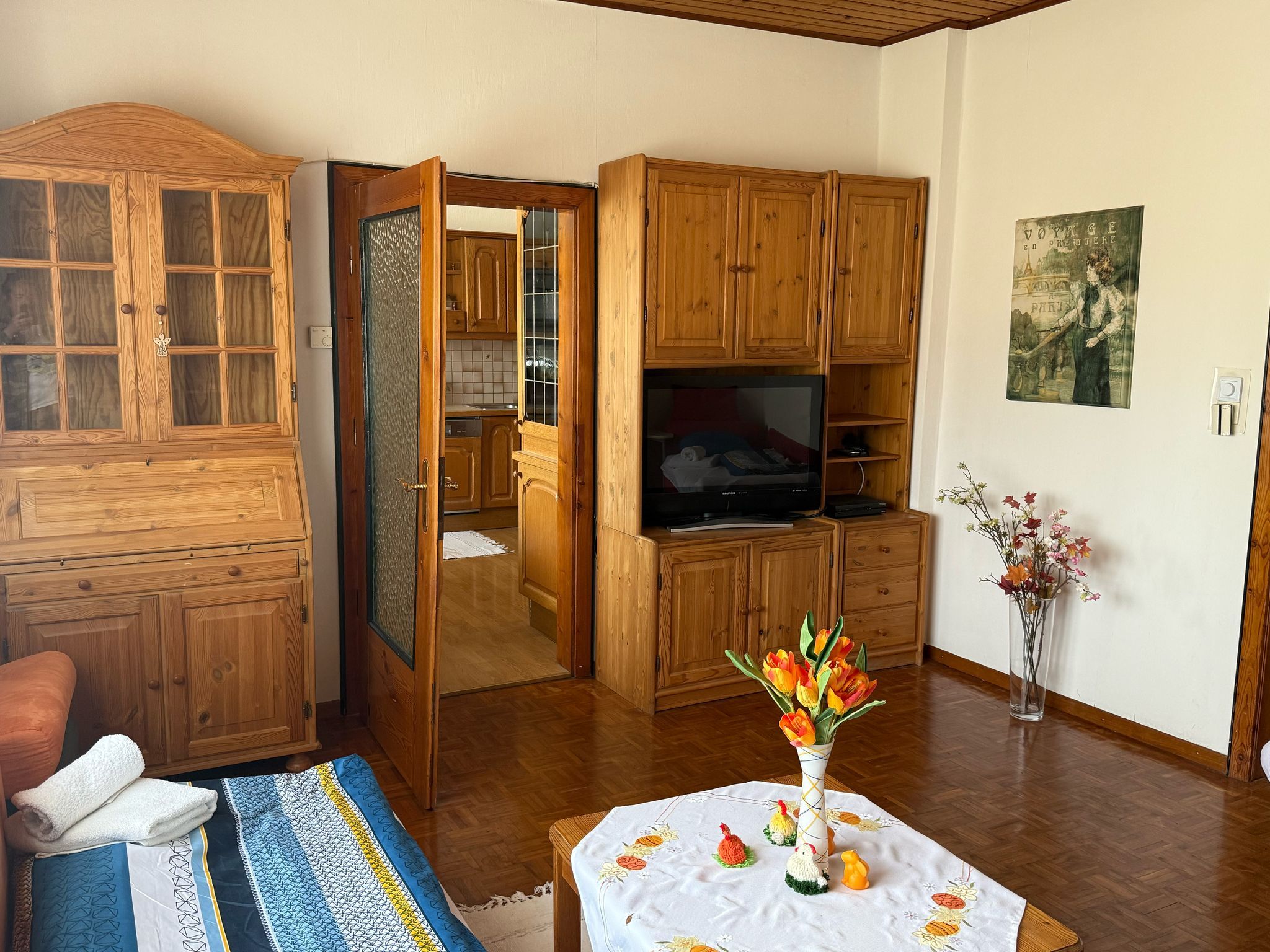 Obývací pokoj s dřevěným nábytkem, stolem s květinami a televizí.