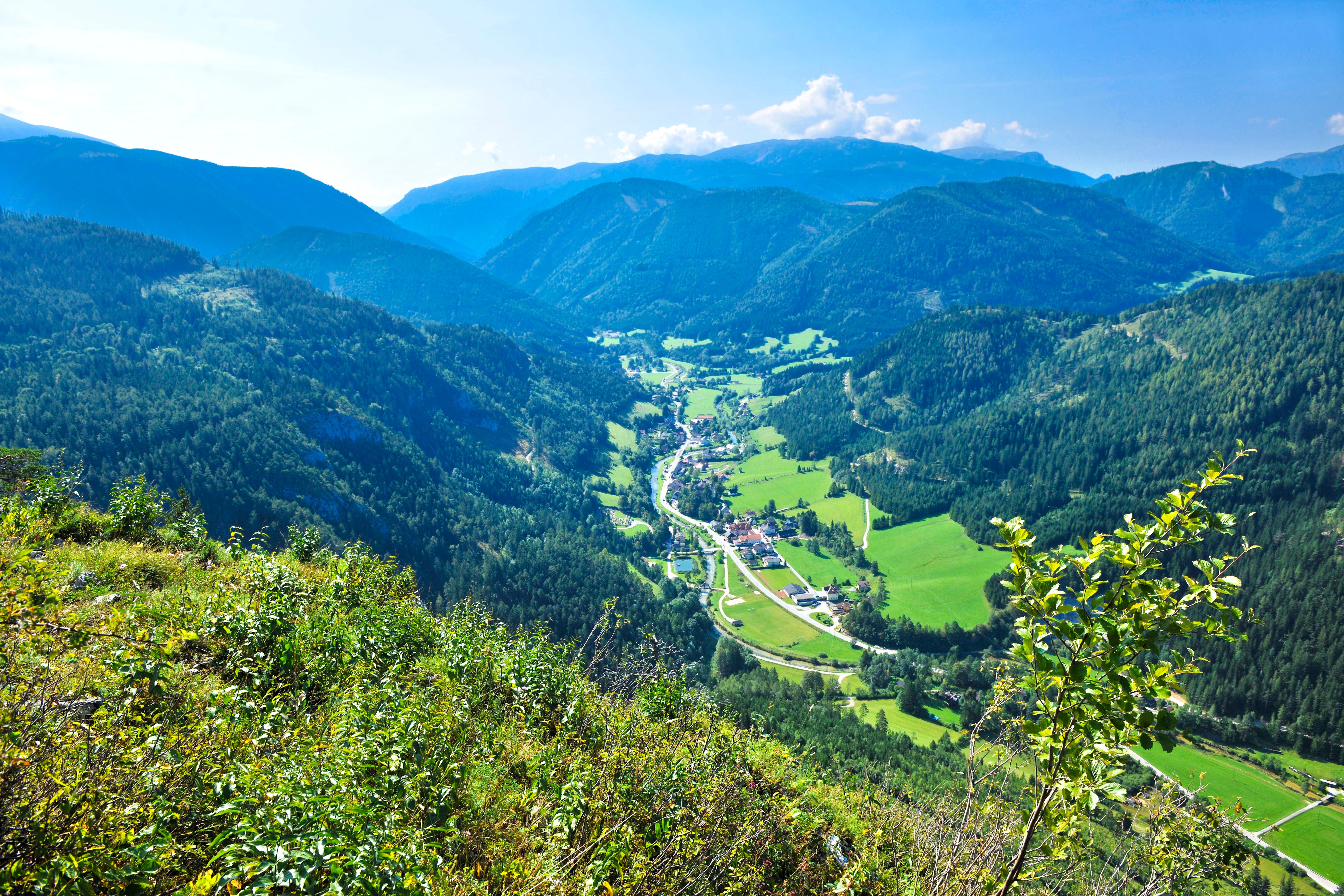 Panoramatický pohled na zelené údolí s horami v pozadí.