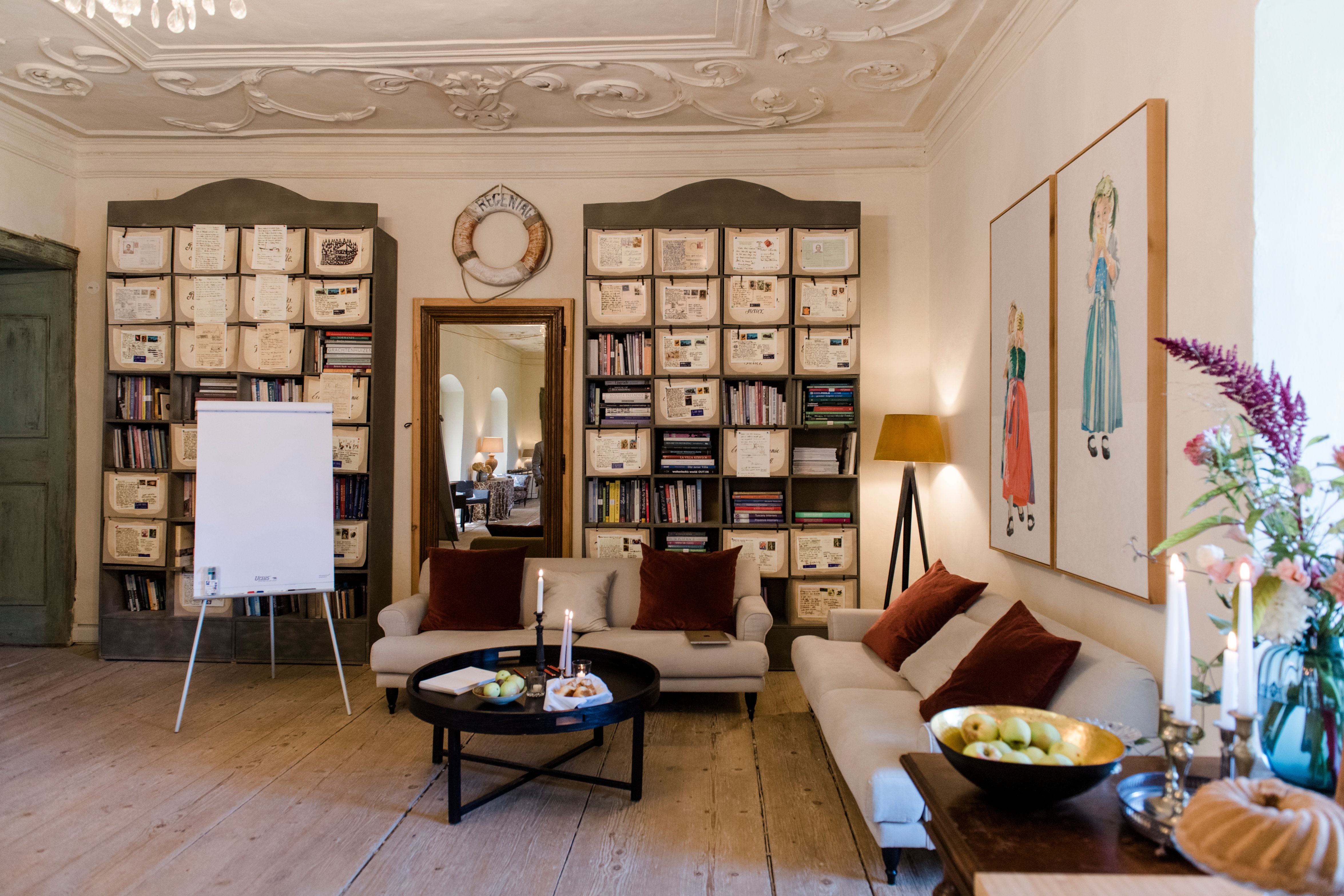 Útulný pokoj s pohovkami, knihovnami a dekoracemi.