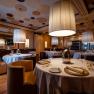 Elegantní restaurace s kulatými stoly, bílými ubrusy a velkými závěsnými lampami.