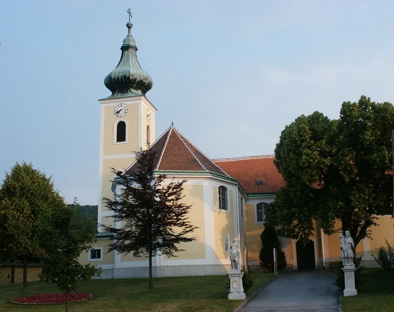 Wolfsthalský poutní kostel s věží a sochami v popředí.