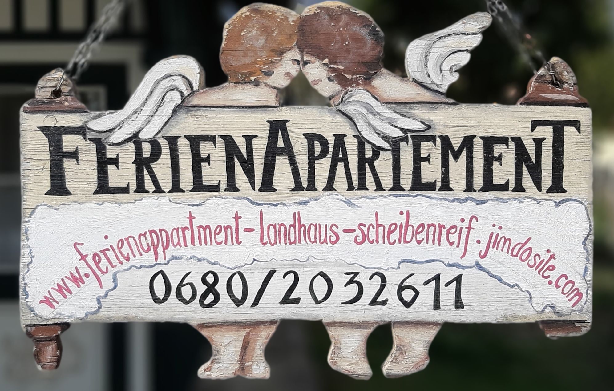 Dřevěná cedule s nápisem "Holiday apartment" a dvěma anděly.