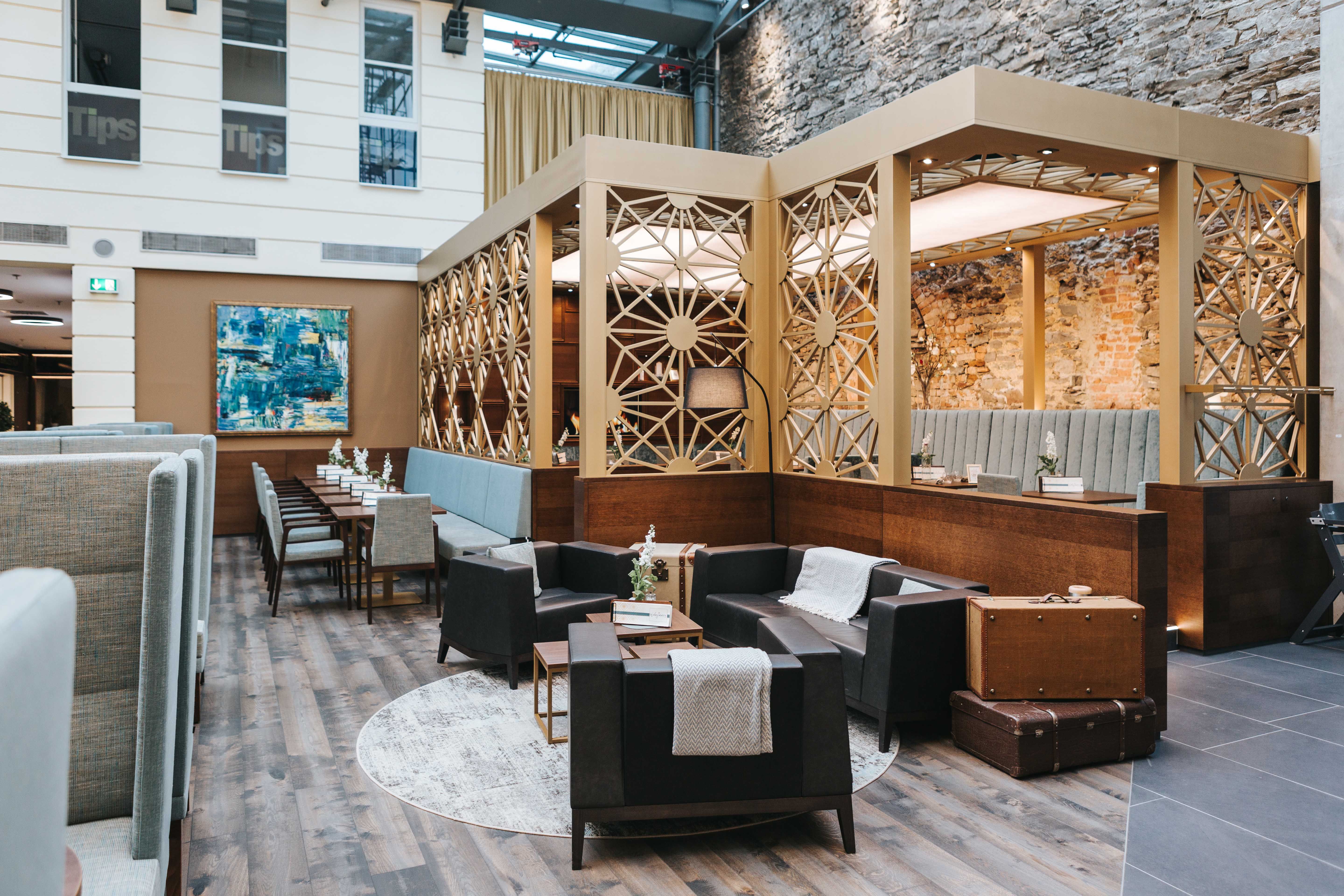 Pohled do interiéru stylové kavárny s moderním nábytkem a dekorativními stěnami.