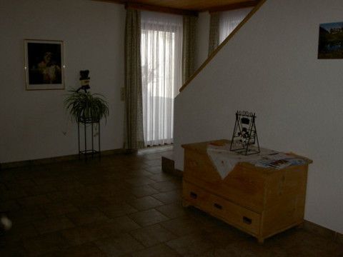 Pohled do interiéru obytného prostoru s dřevěnou skříňkou, rostlinami a schody.