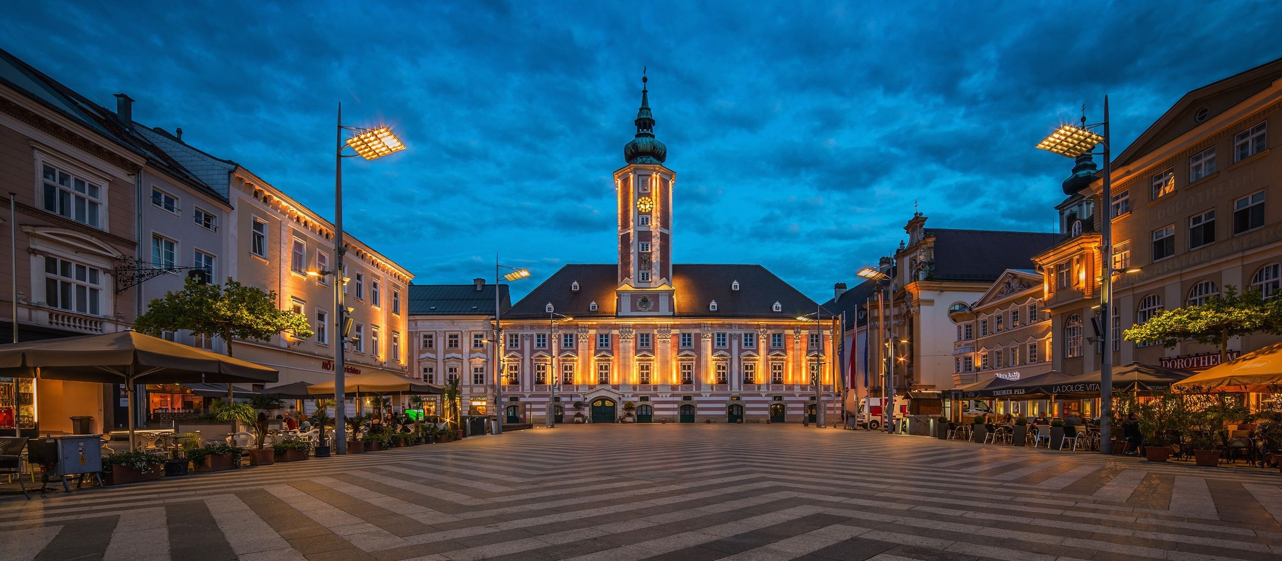 Večerní pohled na osvětlené radniční náměstí v St. Pöltenu s radnicí v pozadí.