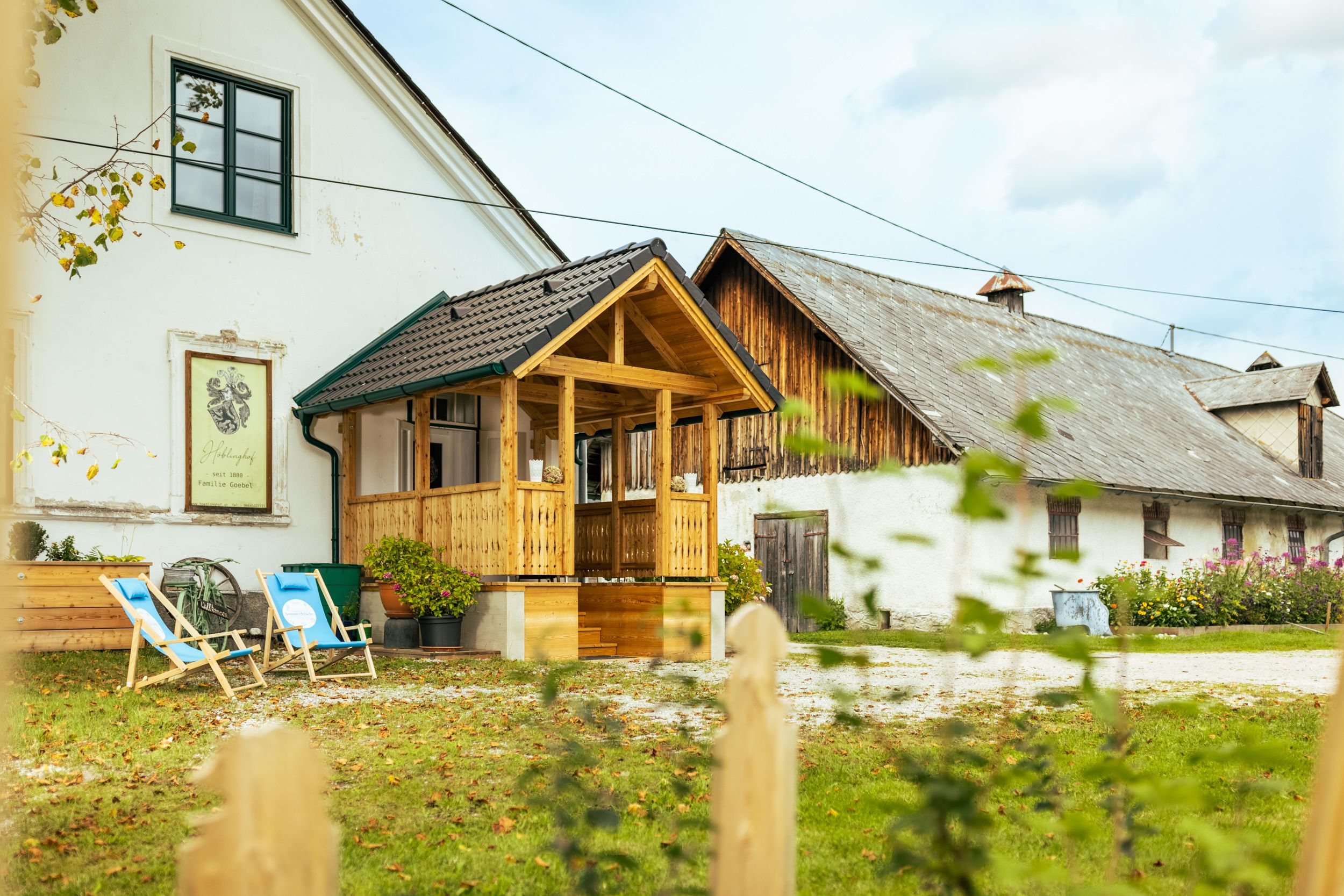 Tradiční statek s dřevěným balkonem a lehátky na zahradě.