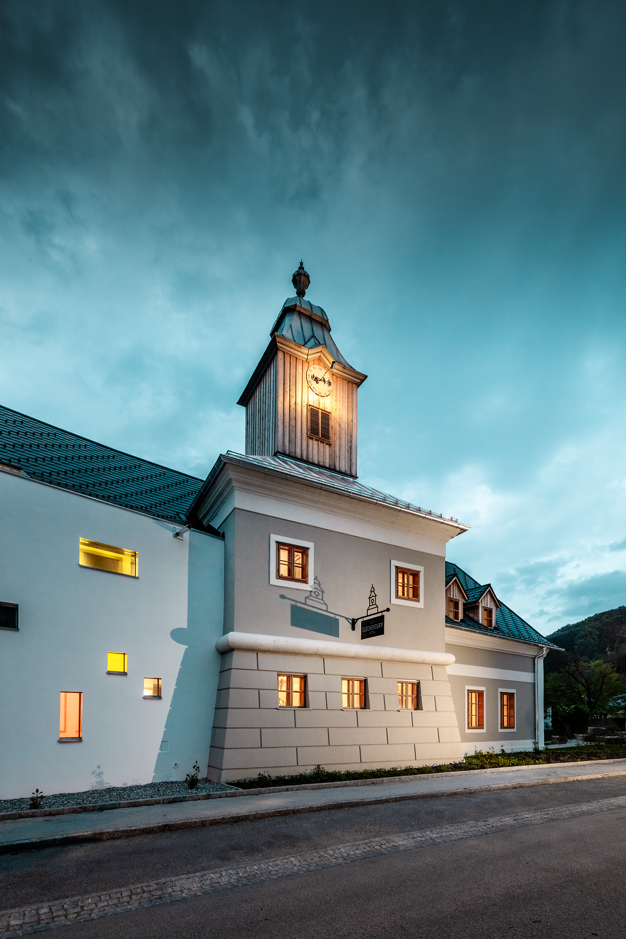 Das Hotel zum Glockenturm strahlt eine einladende Atmosphäre aus, während die sanften Farben der Fassade im Abendlicht leuchten. Die charmante Architektur und der markante Glockenturm laden dazu ein, die Umgebung zu erkunden und die Schönheit der Natur zu genießen.