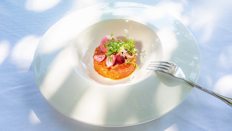 Uměle naaranžovan&yacute; pokrm na b&iacute;l&eacute;m tal&iacute;ři a vedle něj vidlička.