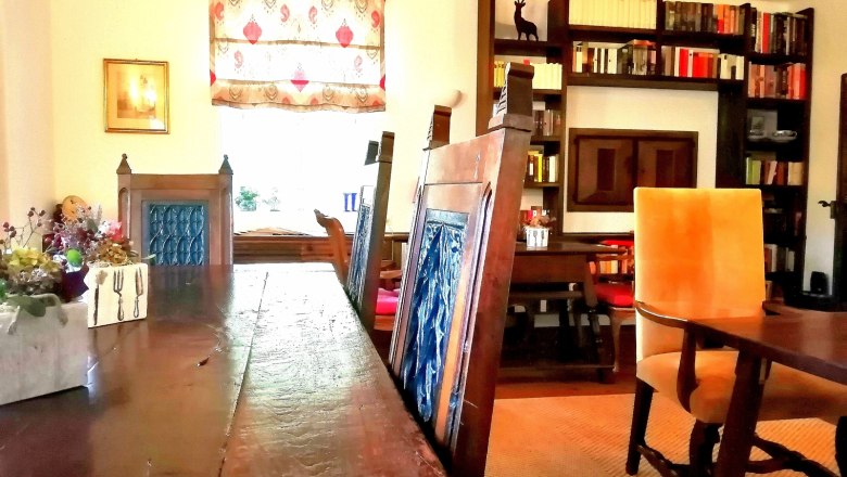 &Uacute;tuln&aacute; sn&iacute;daňov&aacute; m&iacute;stnost s dřevěn&yacute;m stolem, modr&yacute;mi židlemi, knihovnou a ozdobn&yacute;m oknem.