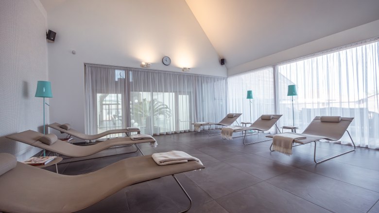 Světlá odpočinková místnost s lehátky a závěsy.