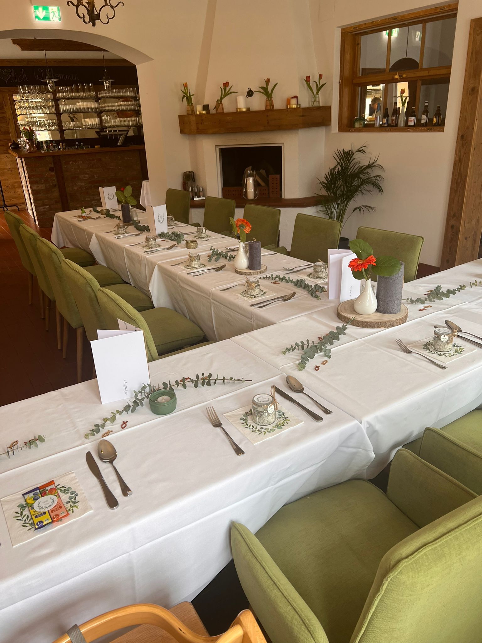 Elegantní restaurace s prostřeným stolem, zelenými židlemi a krbem.