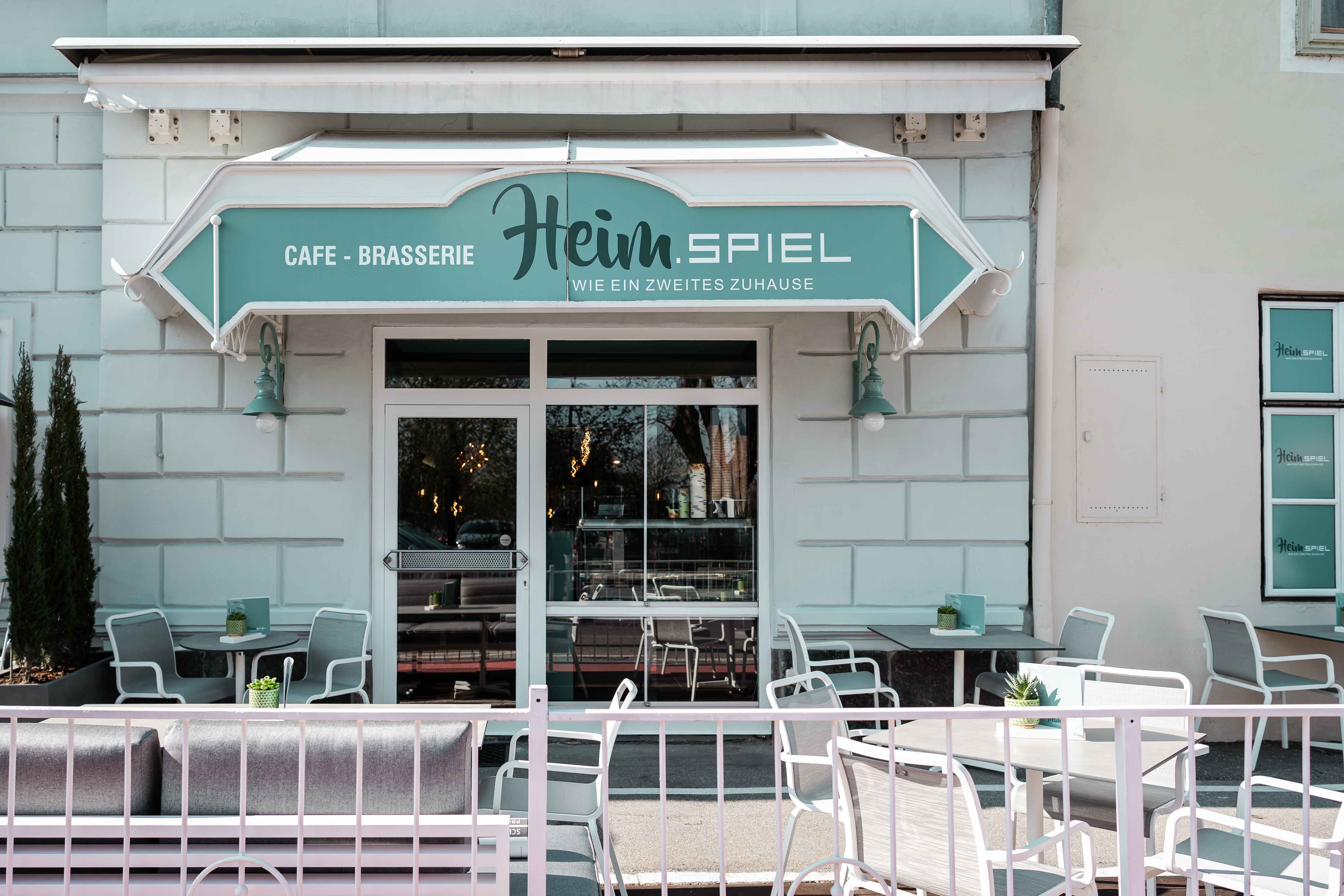 Pohled zvenčí na kavárnu s terasou a posezením.