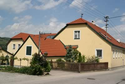 Žlutý dům s červenou střechou ve venkovském prostředí.
