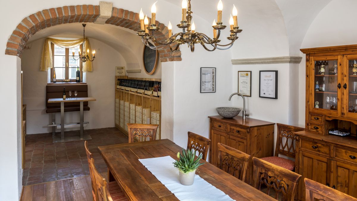 Útulný pokoj s dřevěným nábytkem, lustrem a stojanem na víno.