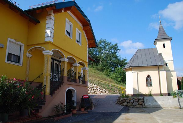 Žlutá budova se schody a vedle ní malý kostel.