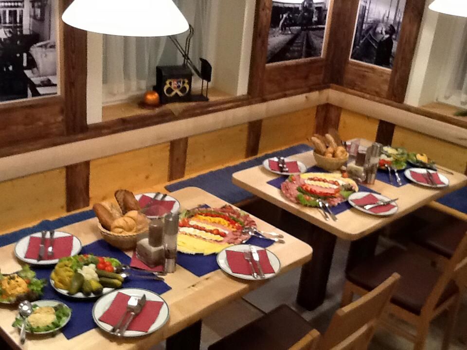 Stůl prostřený v rustikální restauraci s chlebem, uzeninami a saláty.
