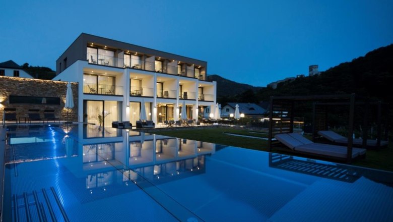 Moderní butikový hotel s nočním osvětlením bazénu.