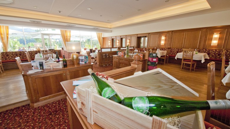 Pohled do interi&eacute;ru elegantn&iacute; restaurace s dřevěn&yacute;m n&aacute;bytkem a lahvemi v&iacute;na.