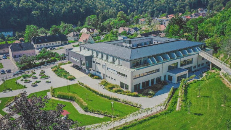 Leteck&yacute; pohled na modern&iacute; budovu se zahradou a okoln&iacute; krajinou.