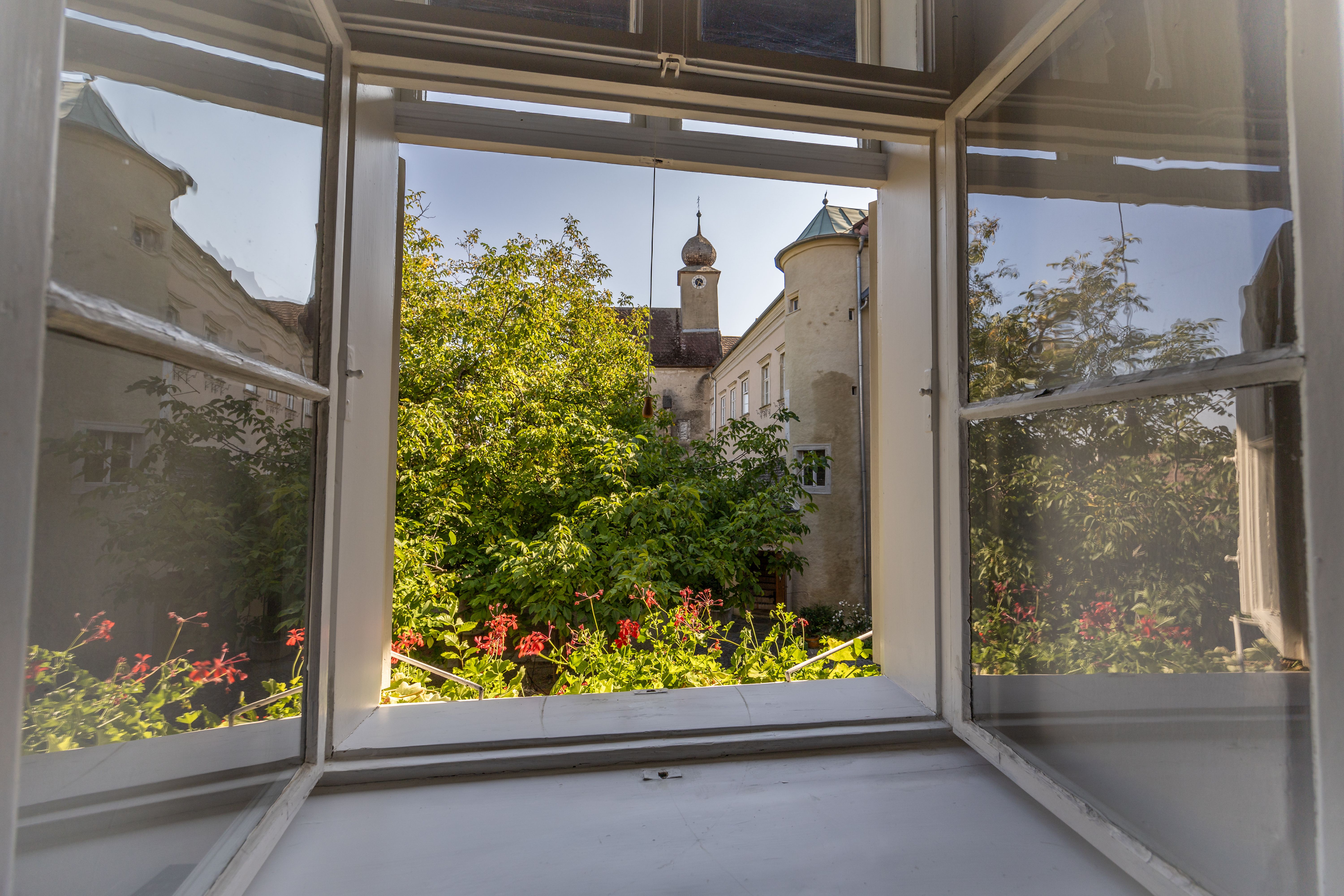 Ložnice s klenutým stropem, dřevěnou podlahou, postelí, křeslem, komodou a kožešinovým kobercem.