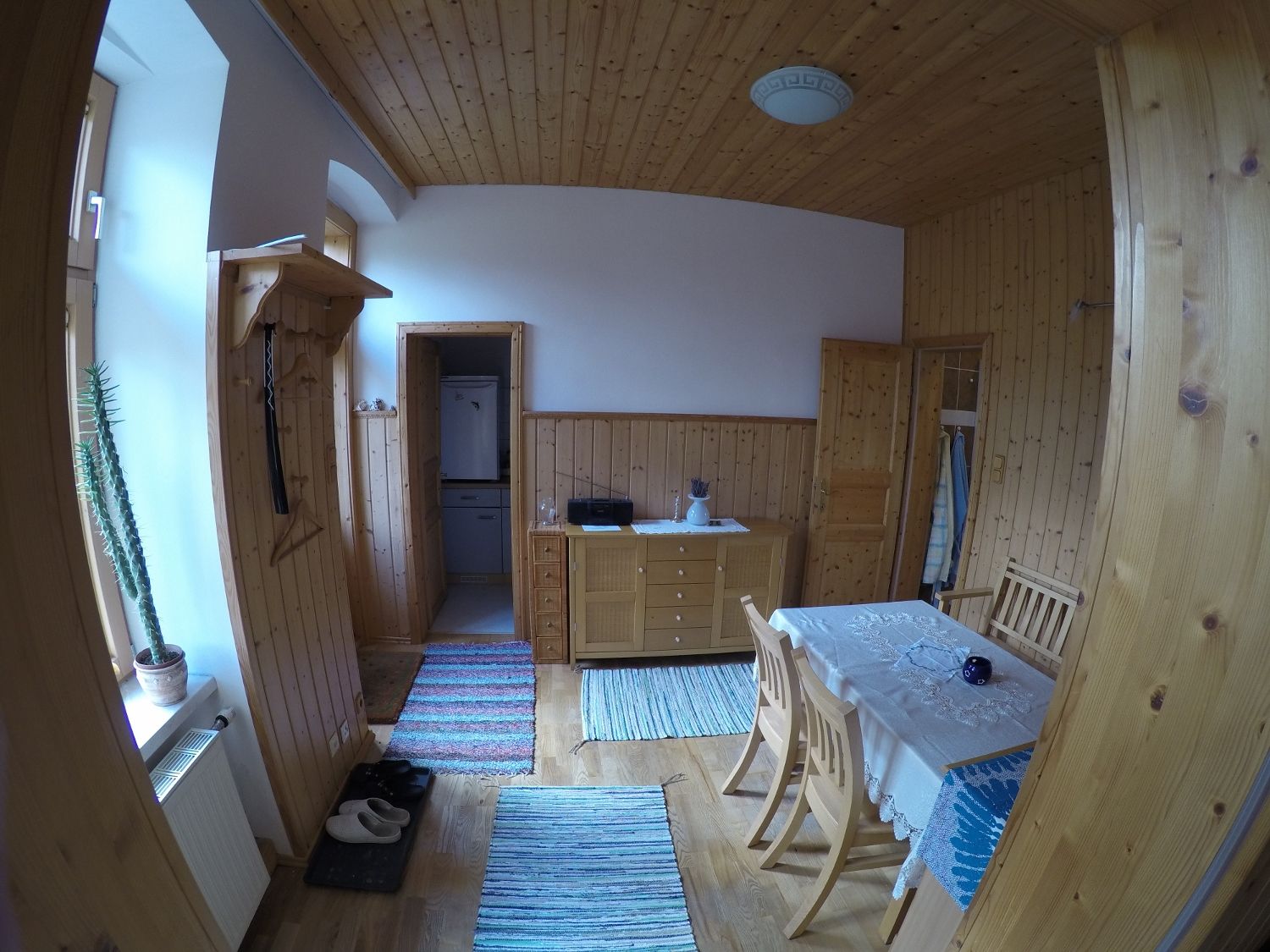 Jídelna v rekreačním bytě s dřevěnými stěnami, jídelním stolem, židlemi a koberci.
