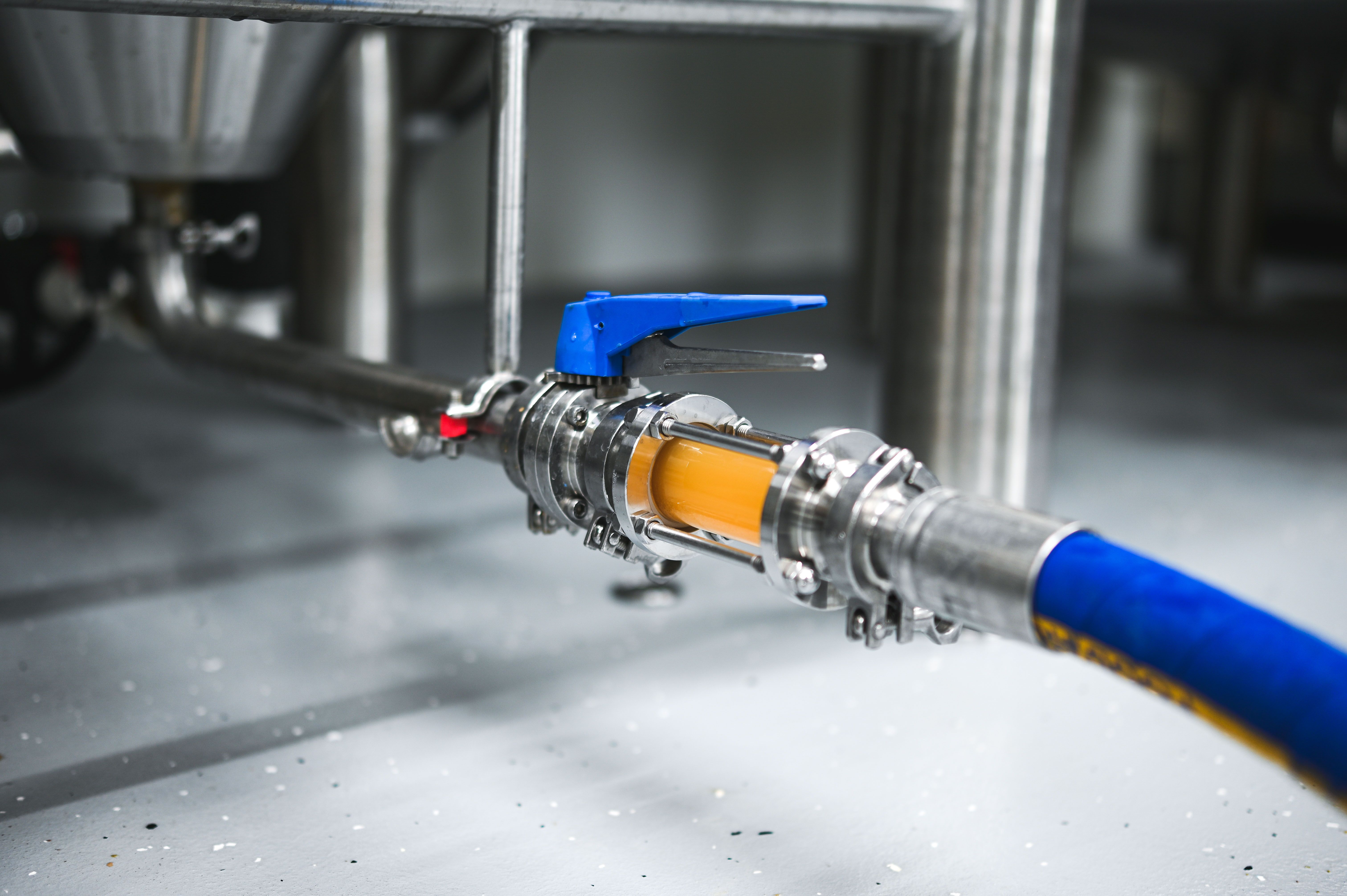 Detailní záběr pivovarské hadice s ventilem a protékající kapalinou.