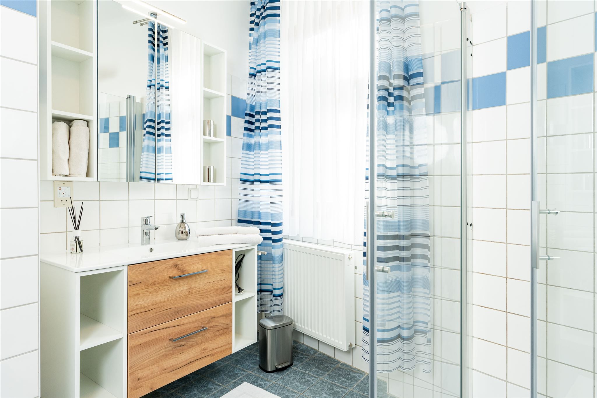 Moderní koupelna s dřevěnou skříňkou, zrcadlem, sprchovým závěsem a obklady.