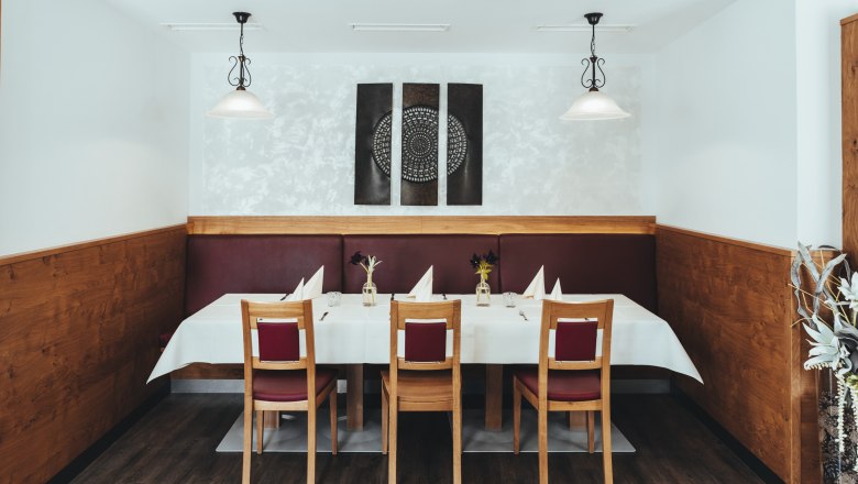 Stylově prostřen&yacute; stůl v restauraci s dřevěn&yacute;m obložen&iacute;m a modern&iacute;m uměn&iacute;m na stěn&aacute;ch.