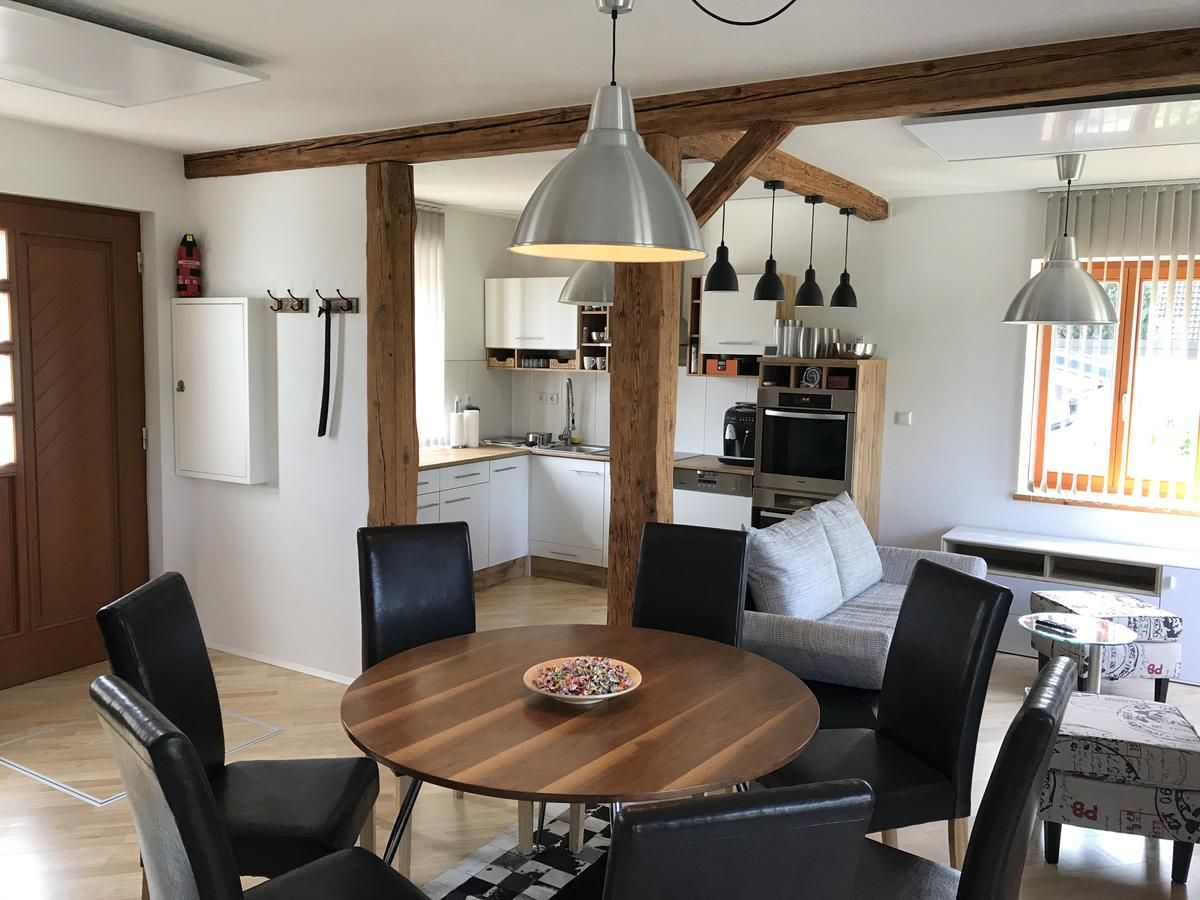 Moderní obývací prostor s jídelním stolem, židlemi, kuchyní a pohovkou.