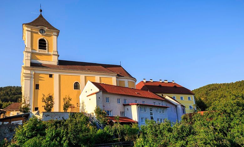 Farní kostel se sousedním klášterem ve slunné krajině.
