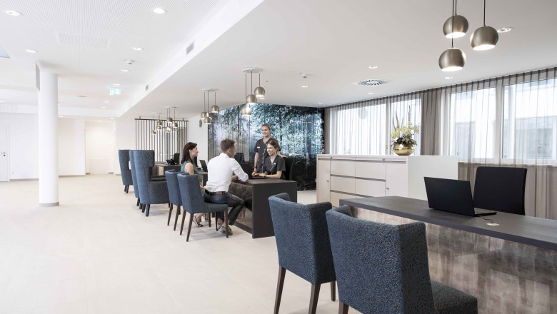 Modern&iacute; recepce s lidmi, kteř&iacute; sed&iacute; u stolu a pov&iacute;daj&iacute; si.