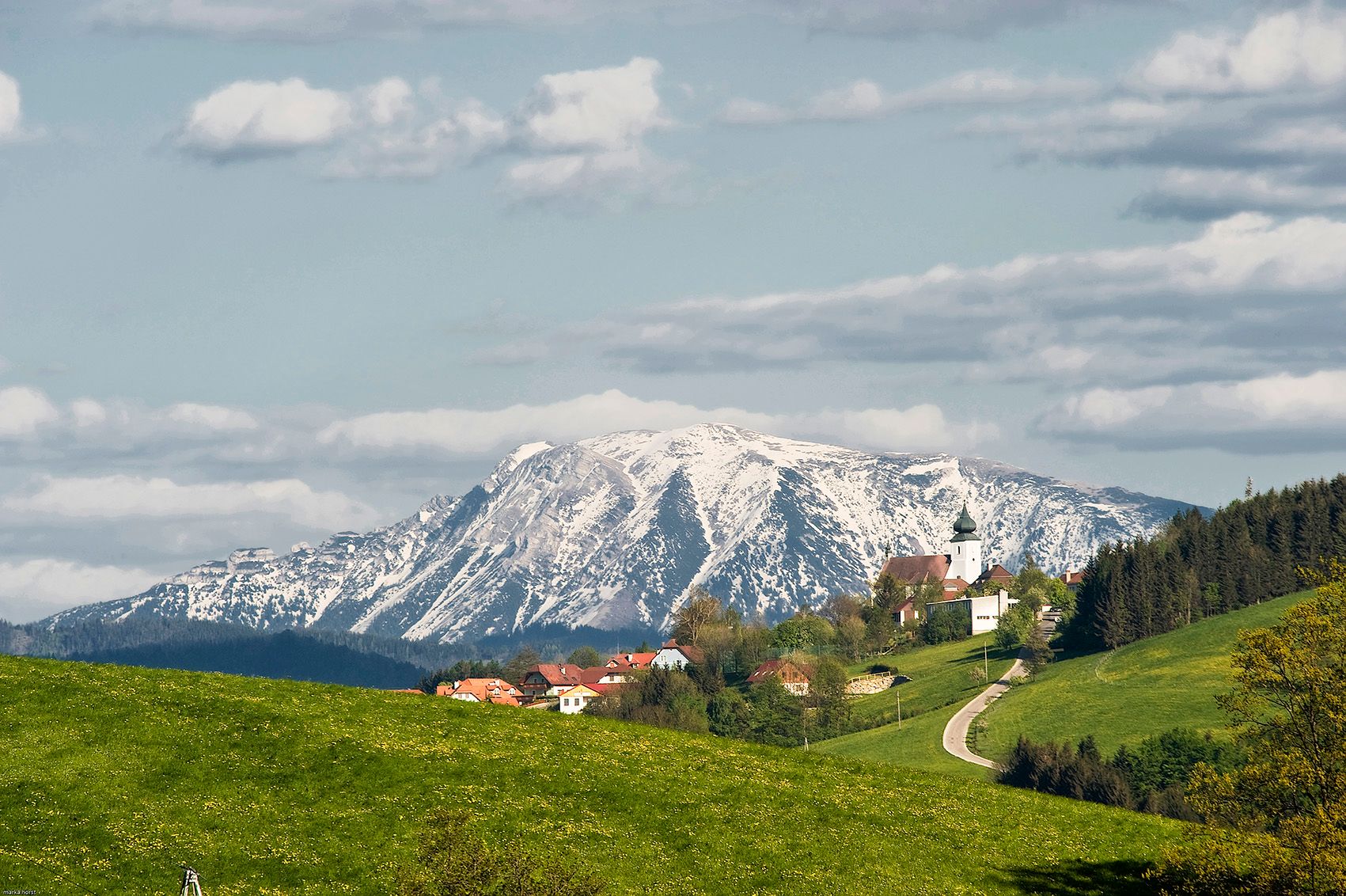 Pohled na St. Leonhard am Walde se zasněženou horou v pozadí.