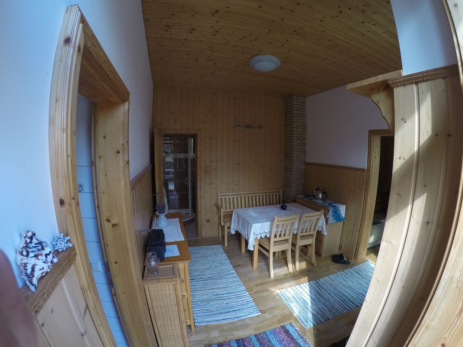 Jídelna s dřevěnými stěnami, stolem a židlemi, koberci a dekoracemi.