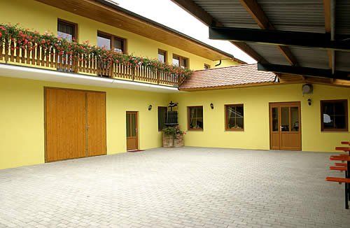 Vnitřní dvůr žluté budovy s dřevěnými dveřmi a balkonem s květinami.