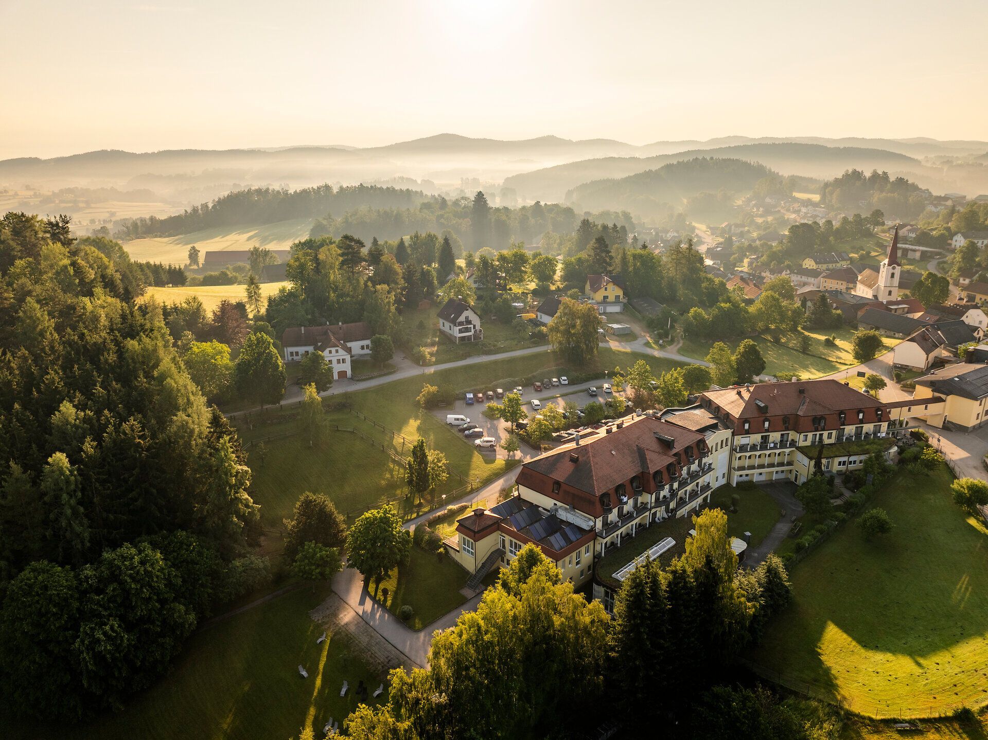 Letecký snímek lázeňského střediska Bad Großpertholz ve Waldviertelu s okolní obcí, loukami a zalesněnými kopci.