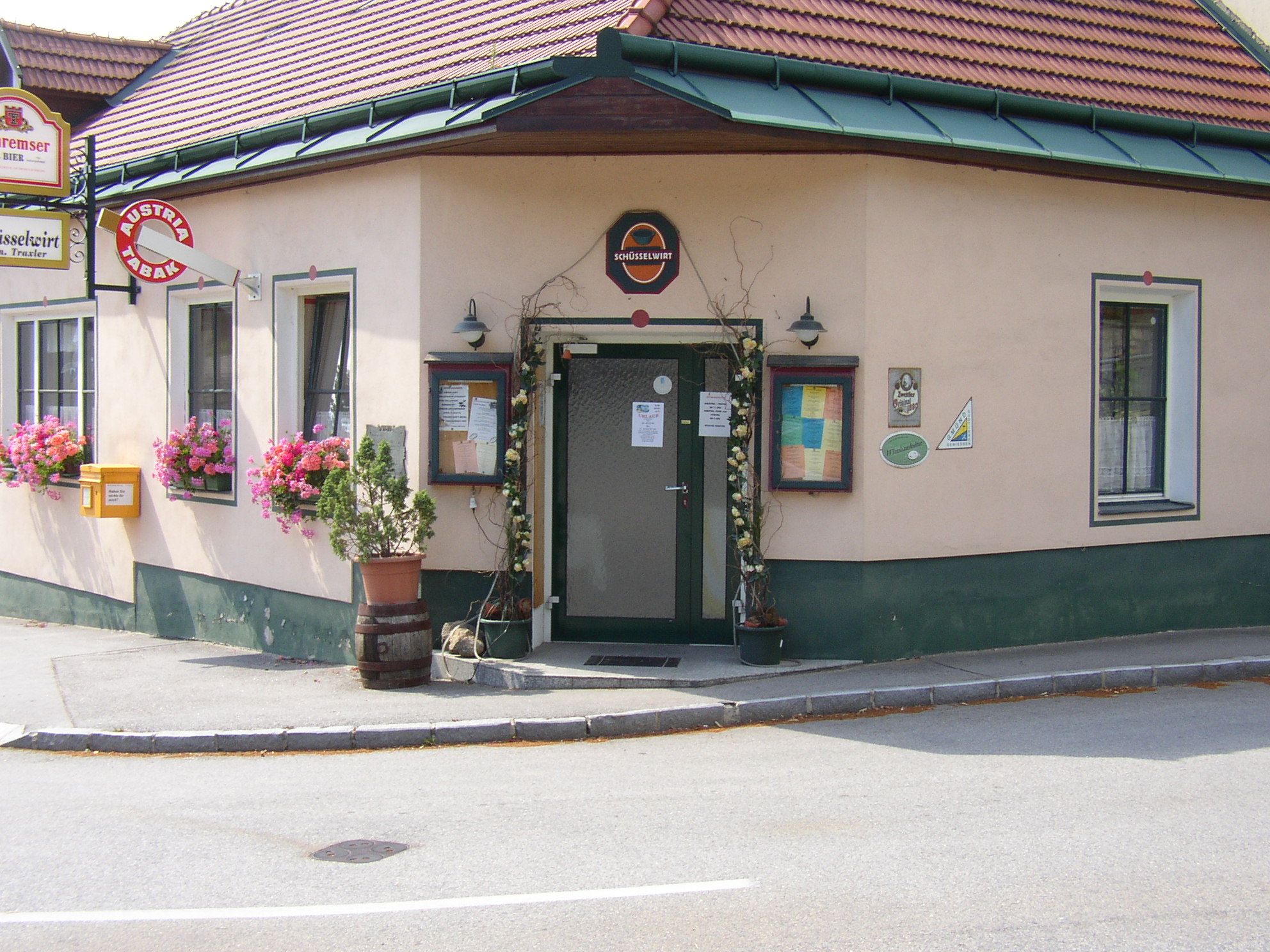 Vchod do tradičního hostince s květinami a nápisy.