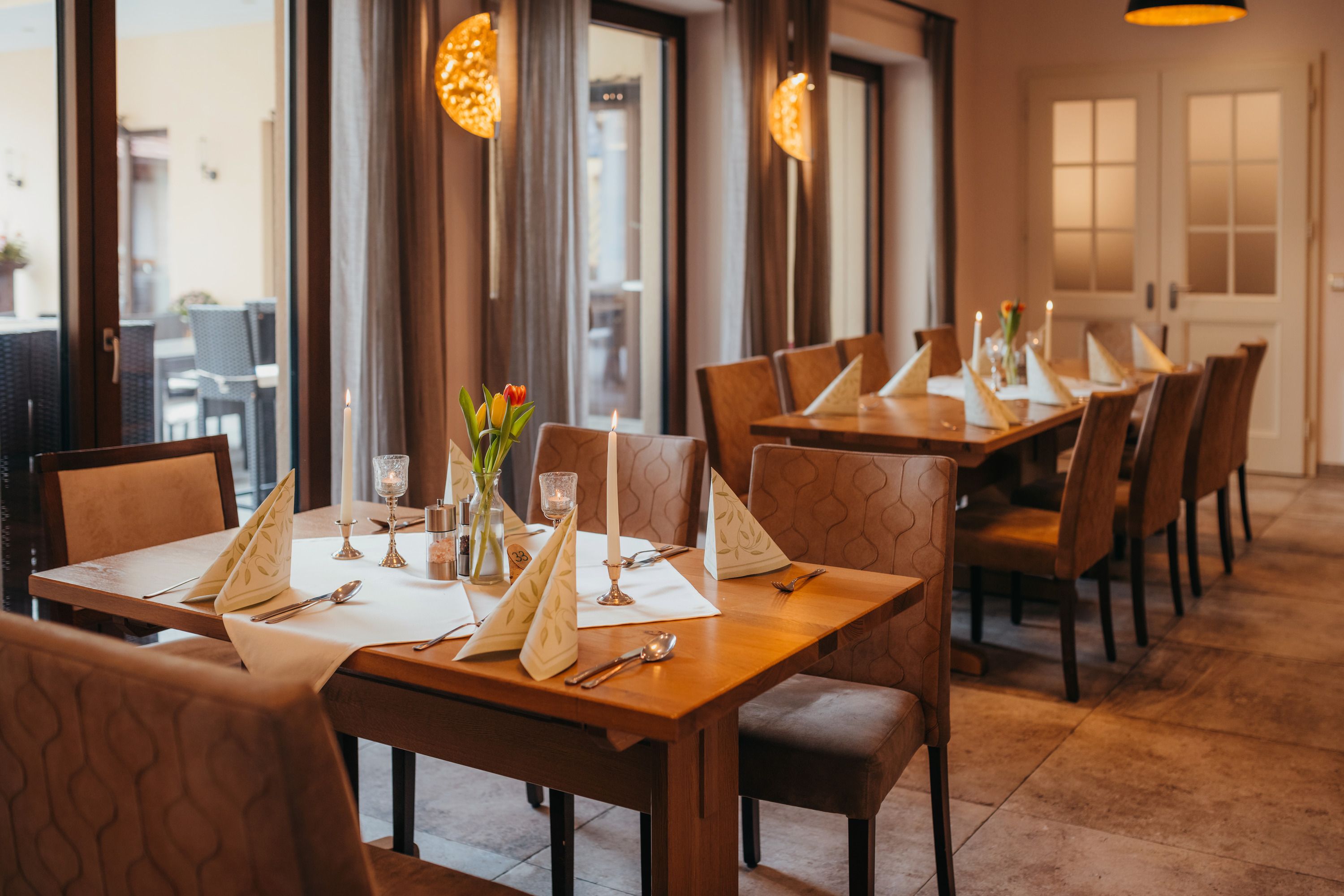 Útulný stůl v hospodě se svíčkami a květinami.