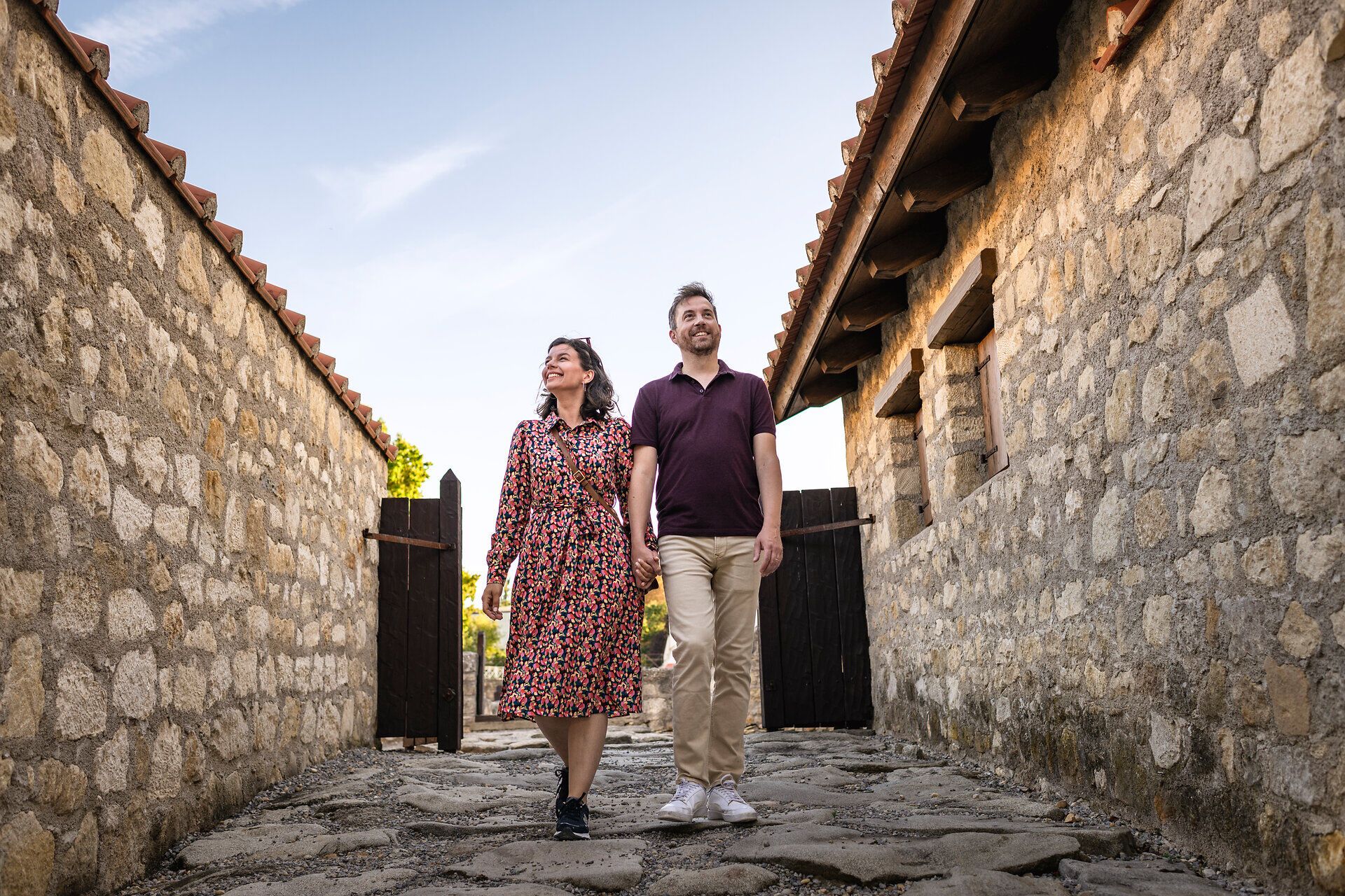 Pár se prochází římskou čtvrtí římského města Carnuntum. Vlevo a vpravo kamenné domy. 