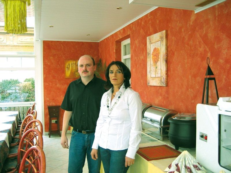 V restauraci s oranžově natřenými stěnami stojí dva lidé.