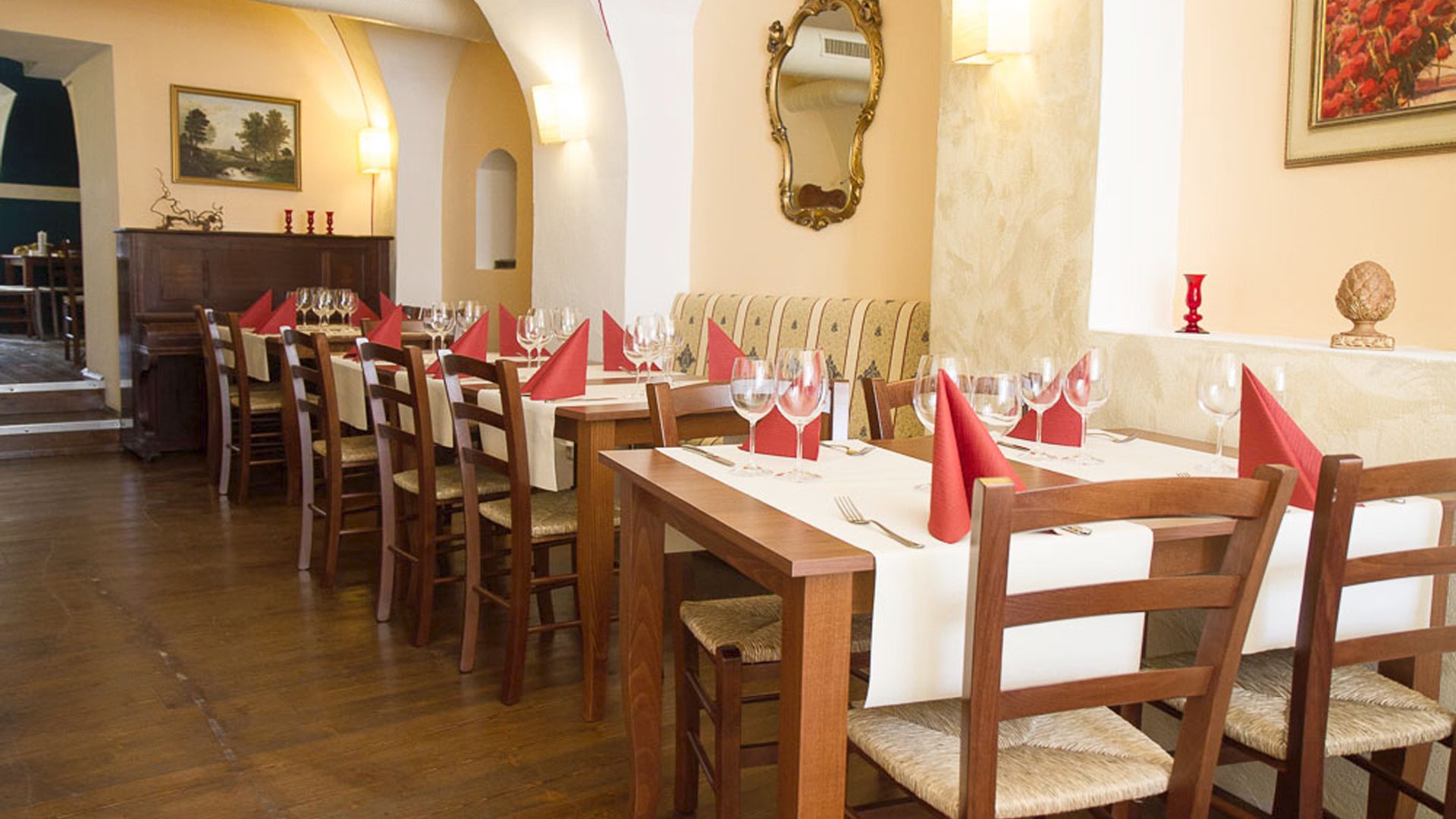Elegantní restaurace s prostřenými stoly a červenými ubrousky.