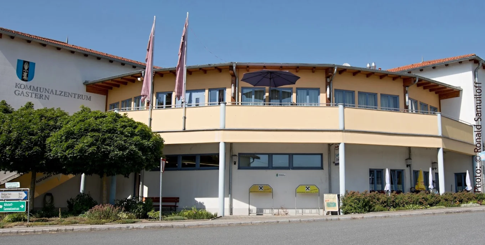 Vnější pohled na komunitní centrum Gastern s modrými okny a žlutou fasádou.